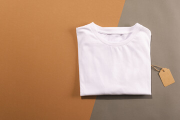 Close up of folded white t shirt with tag and copy space on brown background