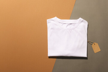 Close up of folded white t shirt with tag and copy space on brown background