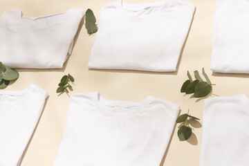 Close up of folded white t shirts with leaves and copy space on yellow background