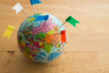 Color flag pins marks on earth globe with wooden table background copy space. Travel holiday...