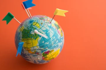 Foto op Plexiglas Noord-Europa Color flag pins marks on earth globe with orange color background copy space. Travel holiday vacation destination, business trip, abroad education, company branch concept.