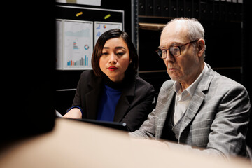 Bookkeeping employees working in administrative file cabinet office surrounded by statistical chart...