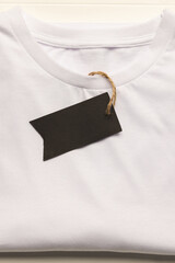 Close up of flat lay of white t shirt with tag and copy space on white boards background