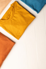 Close up of flat lay of multi coloured t shirts and copy space on white boards background