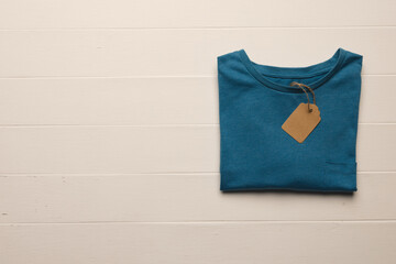 Close up of flat lay of blue t shirt with tag and copy space on white boards background