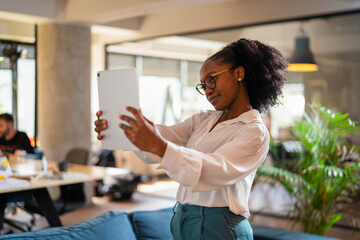 Beautiful African businesswoman in office. Young woman using digital tablet.