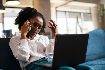 Black businesswoman working on laptop. Portrait of beautiful businesswoman talking to the phone in the office.