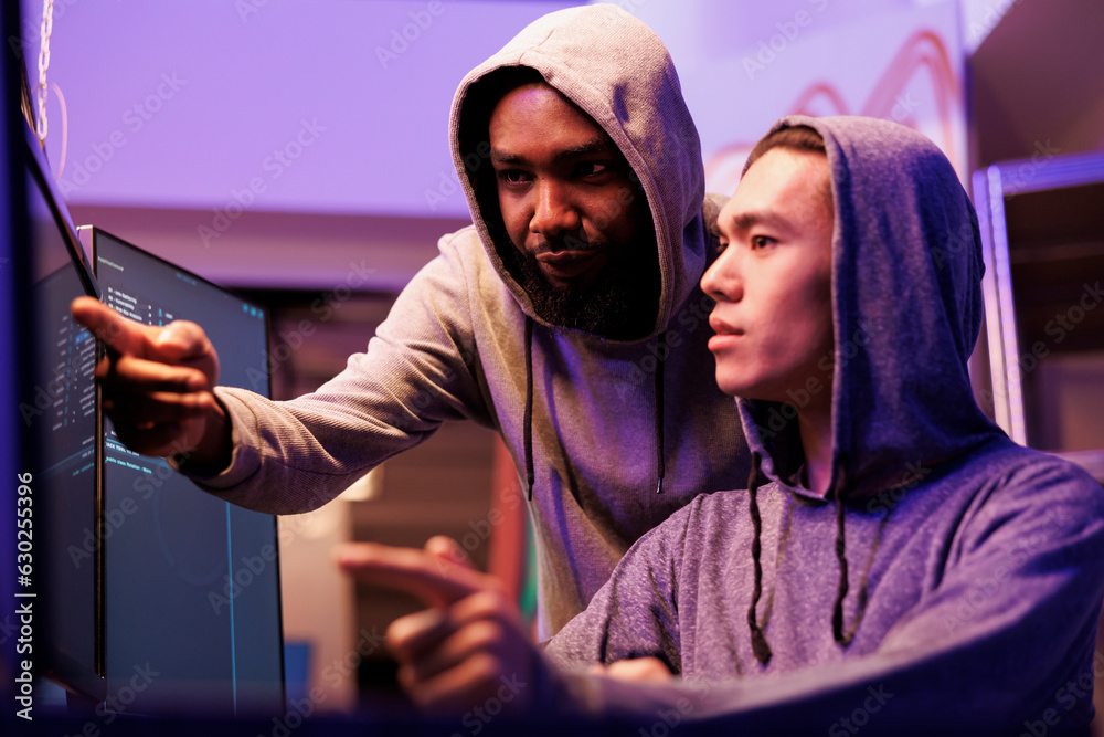Poster hackers checking data after breaking database server together. african american criminal pointing at