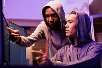 Hackers checking data after breaking database server together. African american criminal pointing...