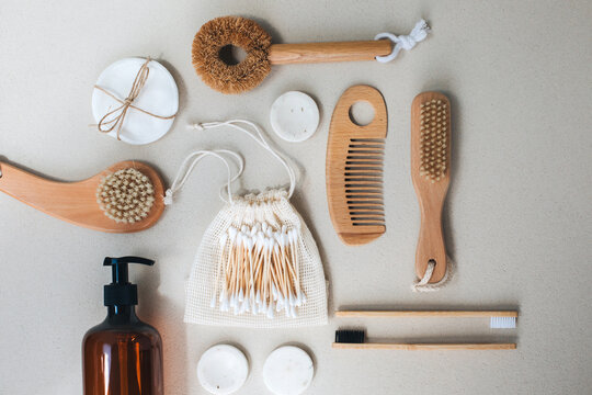 Set of wooden eco friendly devices. Brushes, washcloth and ear sticks, natural soap on a beige concrete background. Flat lay