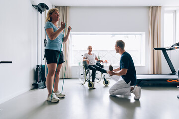 two patients in gym clinic doing rehab exercises with physiotherapist