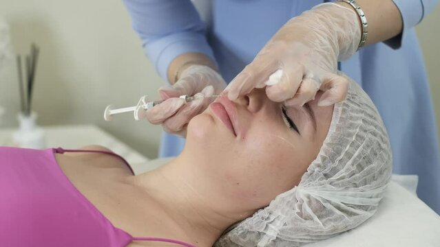 cosmetology specialist in purple gloves carries out injections to strengthen the skin and enhance its appearance. The procedure is performed on a beautiful woman, showing reality of salon facial care