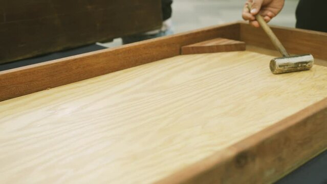 Adults play a wooden board game with a ball and a bat. Close-up.