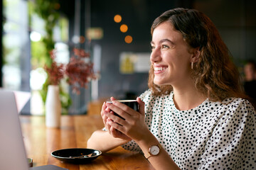 Young Businesswoman With Coffee Working On Laptop Sitting In Cafe Or Office