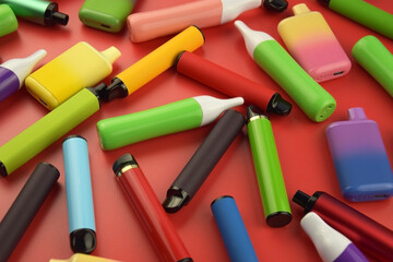 Set of multicolor disposable electronic cigarettes on a red background.