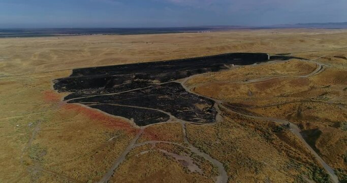 4k drone pan pull back with climb of fresh burn scars from a grass fire. Shot at 60 fps.