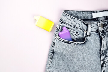 A set of multi-color disposable electronic cigarettes in a jeans pocket.