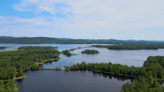 Panning drone shot of islands in an Adirondack lake surrounded by mountains