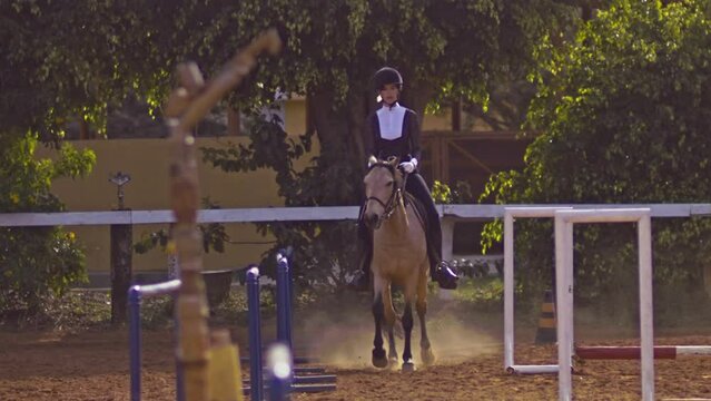 Young Woman in Professional Jockey Suit RIding Hourse In Training Course Holding Reins - Front View Slow Motion 
