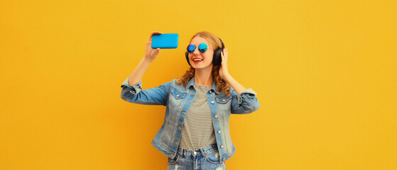 Portrait of happy young woman taking selfie with phone listening to music in wireless headphones...