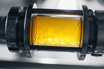 Brewing equipment for quality control, sight glass full of golden beer on stainless steel pipe....