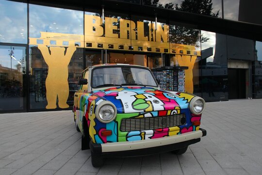 BERLIN, GERMANY - AUGUST 25, 2014: People admire Colorful Trabant 601 car parked in Berlin. 3,096,099 Trabant cars were produced despite their infamous inefficiency and outdated technology.