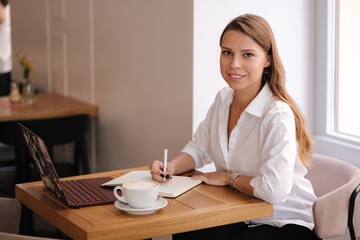 Attractive business lady working in cafe. Female using laptop for studying by video course. 