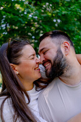 Portrait of a young couple of a man and a woman standing in an embrace and kissing during a date on the background of a park plus size model