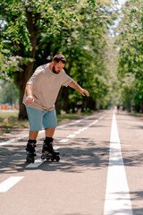 Young guy with a beard learns to rollerblade in a city park concept of wanting to learn new things...