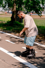 Young guy with a beard learns to rollerblade in a city park concept of wanting to learn new things...