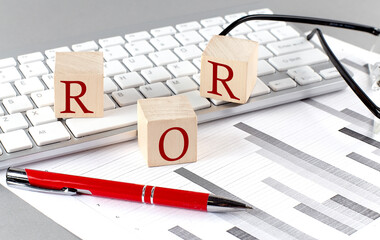 ROR written on a wooden cube on the keyboard with chart on grey background