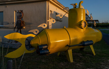 Saint-Aubin-Sur-Mer, France - 07 17 2023: A diver and a yellow submarine along the jetty from the beach at sunset in a golden light.