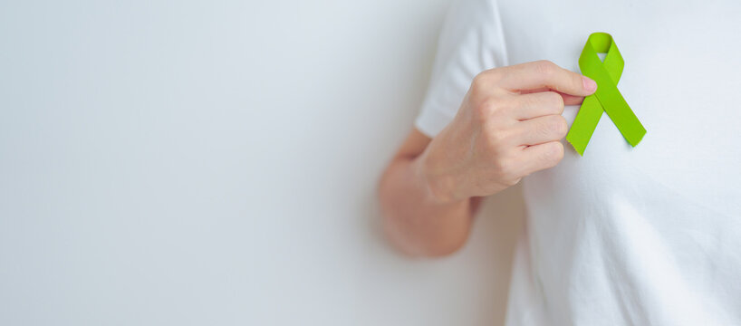 Woman holding green Ribbon for world Lymphoma Awareness September month, world Mental Health Day, Liver, Gallbladders, bile duct, cervical, kidney Cancer. Healthcare and world cancer day concept