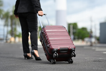 Cropped shot of unrecognizable woman walking near the airport with a suitcase. Business travel...