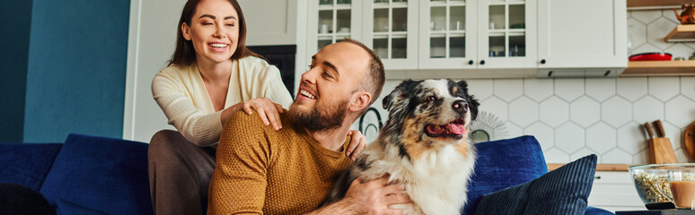 Smiling woman spending time with boyfriend and border collie near coffee and popcorn at home, banner