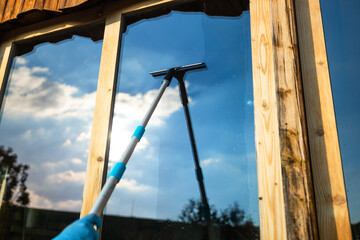 Cropped view of woman hand equipment for washing and cleaning the window from the outside