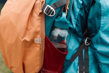 Close up of woman with water bottle in backpack pocket. Travel, tourism, hike and people concept....