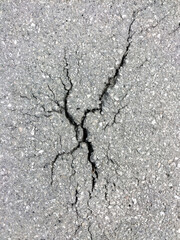 A crack with splits in different directions in the old asphalt on the road. Top view