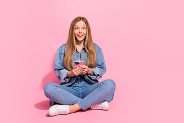 Photo of astonished cheerful girl wear trendy clothes sit floor buy iphone rejoice purchase empty...