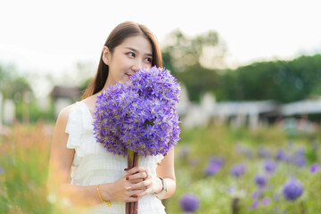 Young Asian tourist holding purple flowers resting and enjoying the hydrangea field in full bloom Lifestyle girl picking hydrangeas in the garden in Chiang Mai, Thailand..