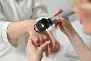 Obraz na płótnie Canvas Beautician examine the skin on the female hand with a dermatoscope