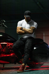 Athletic bearded biker man riding motorbike isolated on indoor parking
