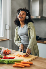 Multiracial woman sings while cooking in the kitchen.