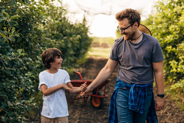 Happy moment in the orchard with father and his son.