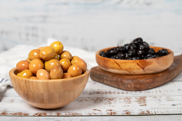 Green and black olives at wooden bowl. Olives on a white wood background. Mediterranean food. vegan food