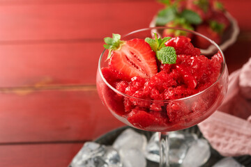 Strawberry granita or fresh berry sorbet in glass on old red wooden table background. Texture of ice cream or sorbet. Ice cream with strawberry and mint. Sorbet recipe. Summer treat. Selective focus. - obrazy, fototapety, plakaty