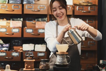 Cheerful woman making a coffee cup in cafe,Barista holding a cup of hot coffee for the first Morning.