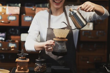 Cheerful woman making a coffee cup in cafe,Barista holding a cup of hot coffee for the first Morning.