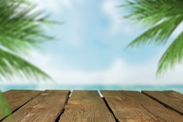 Fototapeta na wymiar Empty wood desk over sea and palm leaves