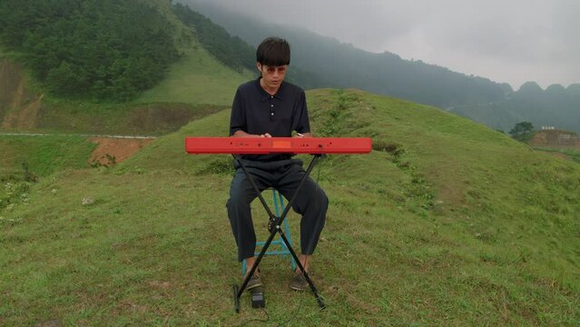 Keyboard player sitting down playing instrument. Picturesque landscape